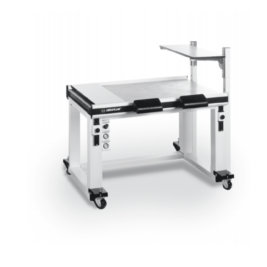 A Vibraplane table with a metal frame on caster wheels. It features an adjustable surface, control panel, and handles on both sides. An angled support shelf is attached on the right.